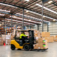 A photo of a forklift driving in a warehouse.