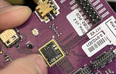 A photo of a person holding a microchip mounted on a circuit board.