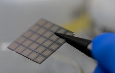 A photo of a pair of tweezers holding a computer chip.