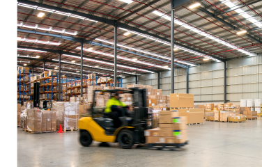 A photo of a forklift driving in a warehouse.